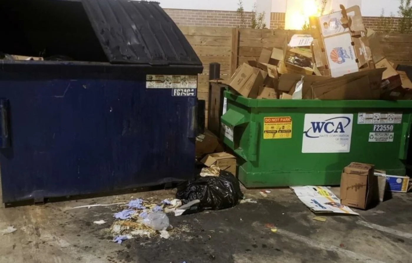 Unsanitary dumpster enclosure with litter, grease stains, overflowing recycling container, and dirty concrete requiring commercial pressure washing services in Mooresville NC